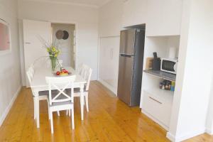 cocina con mesa blanca, sillas y nevera en Cosy 3 bedroom cottage with indoor fireplace, en Romsey
