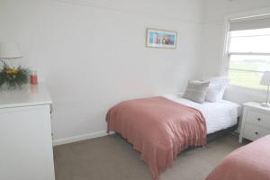 a white bedroom with a bed and a window at Cosy 3 bedroom cottage with indoor fireplace in Romsey