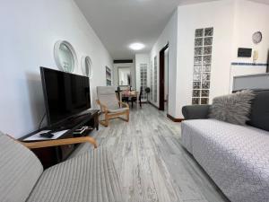 sala de estar con sofá y TV de pantalla plana en LAS CANTERAS Sabor a Mar 2 Dormitorios "Parking Gratis", en Las Palmas de Gran Canaria