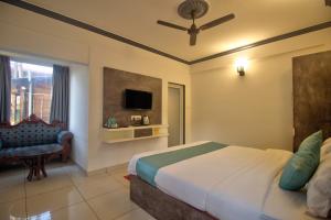 a bedroom with a bed and a tv and a chair at Oceano Beach Resort in Arambol