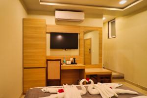 a hotel room with a television and towels on a bed at Clarks Inn Express Udaipur in Udaipur
