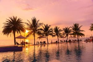 a resort pool with palm trees and a sunset at Sun Viet Resort Phu Quoc in Phu Quoc