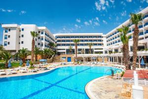 a resort with a large swimming pool in front of a building at Ascos Coral Beach Hotel in Coral Bay