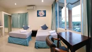 a hotel room with two beds and a desk and a table at Marina Seaview Krabi in Krabi town