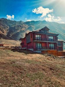 a house on a hill with mountains in the background at Kazbegi Stylish Apartment in Kazbegi