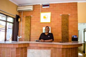 a woman standing at a counter in a brick wall at Happy Rhino Lodge in Arusha