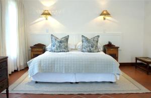 a bedroom with a white bed with blue pillows at Budmarsh Country Lodge in Magaliesburg