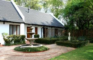 a garden with a fountain in front of a house at Budmarsh Country Lodge in Magaliesburg