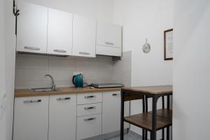 Vico 11 في جيتا: مطبخ بدولاب بيضاء وطاولة خشبية