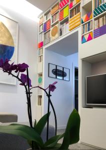 un salon avec une plante et un mur avec des livres dans l'établissement Lily Apartment Napoli, à Naples