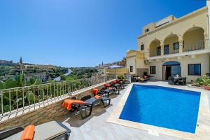 a villa with a swimming pool and patio furniture at The Harbour Holiday Home in Għajnsielem