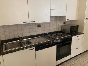 a kitchen with a sink and a stove and white cabinets at Casa De Pellegrin Bellagio Lake Como in Bellagio
