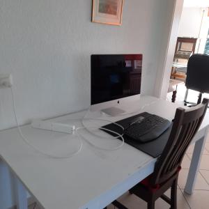 a white desk with a computer on top of it at Business traveller's dream apartment in Bevaix