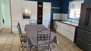 a kitchen with a table and chairs and a refrigerator at Maison familiale avec jardin clos et barbecue in Le Puy en Velay