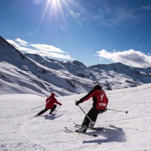 dos personas están esquiando por una montaña cubierta de nieve en ESQUÍ PIRINEO ARAGONÉS APARTAMENTO EL JUNCARAL Wifi, en Villanúa