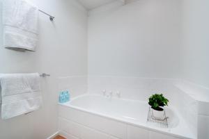 Baño blanco con bañera y maceta en Dromana Beach Holiday House *3 minutes to the sand, en Safety Beach