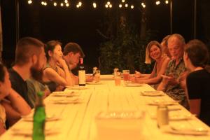 een groep mensen die rond een lange tafel zitten bij Barefoot Project formerly Baan Klong Kleng in Ko Phayam