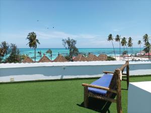 a bench sitting on a lawn with the ocean in the background at Zanzicrown in Nungwi