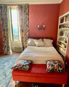 a bedroom with a bed with a red wall at Chambre avec vue in Saignon