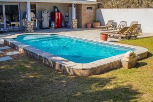 a swimming pool with a deck and a patio at Anchorage River House in Stilbaai