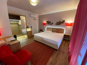 ein Schlafzimmer mit einem weißen Bett und einem roten Stuhl in der Unterkunft Hotel Hessischer Hof in Butzbach