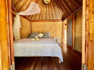 een slaapkamer met een bed in een strohut bij Rumah Canaria Bungalow in Gili Trawangan