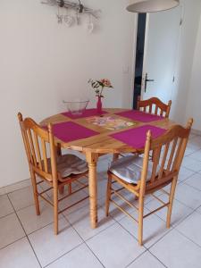 uma mesa de madeira com duas cadeiras e uma toalha de mesa roxa em L'Auberge em Abjat