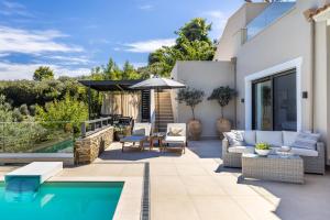 un patio con piscina, sillas y sombrilla en Villa Politimi Luxury Retreat, en Skopelos Town