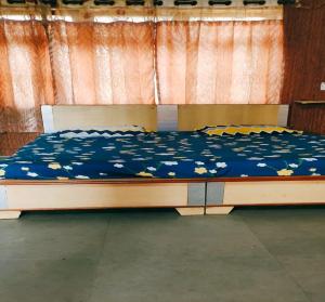 a bed with a blue comforter with flowers on it at Jiya Green Garden & Banquet, Sonipat in Sonīpat