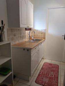 uma cozinha com armários brancos, um lavatório e um tapete vermelho em L'Auberge em Abjat