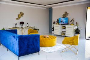 a living room with blue and yellow furniture and a tv at La mbeu concierge in Thohoyandou