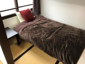 een bed in een slaapkamer met een rood kussen erop bij Cool-Residence OTARU in Otaru