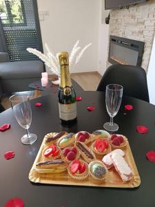 - une bouteille de champagne et une assiette de nourriture sur une table dans l'établissement Évasion avec jacuzzi intérieur, à Rosières-près-Troyes