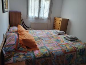 ein Schlafzimmer mit einem Bett mit einer bunten Decke und einer Kommode in der Unterkunft Habitación privada in Castro-Urdiales