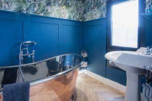 a blue bathroom with a tub and a sink at The Langland bay look out in Swansea