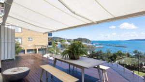 een balkon met een tafel en uitzicht op het water bij Riviera - Panoramic Water Views In The Heart Of Nelson Bay in Nelson Bay