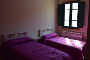 two beds in a room with purple sheets at Tras do convento in Samos