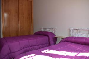 2 camas en una habitación con sábanas moradas en Tras do convento, en Samos