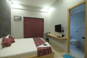 1 dormitorio con 1 cama, TV y baño en Nk7 Lake Town, en Calcuta