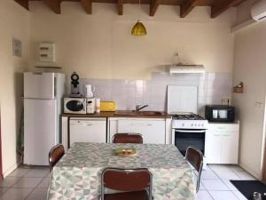 una cucina con tavolo e sedie e una cucina con elettrodomestici bianchi di Gîte indépendant au calme avec vue panoramique a Rocamadour