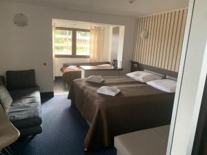 um quarto de hotel com duas camas e um sofá em Hotel Alpenrose Gerlitzen em Treffen