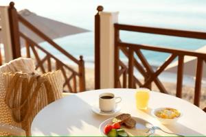 einen Tisch mit einem Teller Essen und einer Tasse Orangensaft in der Unterkunft Potokaki Beachfront Hotel in Pythagoreio