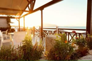 eine Terrasse mit einem Tisch, Stühlen und Pflanzen in der Unterkunft Potokaki Beachfront Hotel in Pythagoreio
