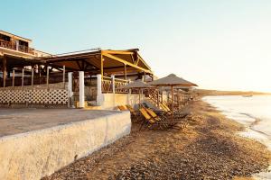 eine Gruppe von Stühlen und Sonnenschirmen am Strand in der Unterkunft Potokaki Beachfront Hotel in Pythagoreio