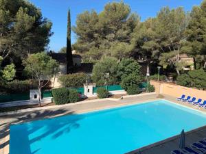 a large swimming pool with blue chairs and trees at Les Appartements de La Marina in Sanary-sur-Mer