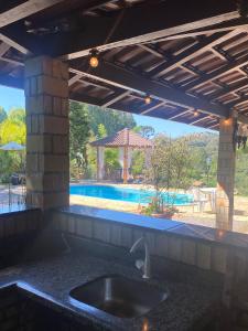 uma cozinha com um lavatório e uma piscina em Sítio dos Coqueiros, em meio a natureza com piscina em Carlos Barbosa