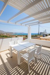 Bella Karpathos Villas في كارباثوس: طاولة بيضاء وكراسي على فناء مع اطلالة