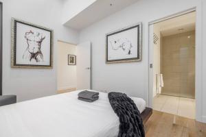 a bedroom with a white bed and a walk in shower at The Sophia in Melbourne