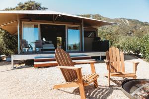 duas cadeiras sentadas em frente a uma casa em Drift Off Grid Luxury Eco Glamping em Tarakohe