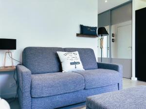 un sofá azul en una sala de estar con una almohada en Studio & Spa La Discrète, en Saint-Évarzec